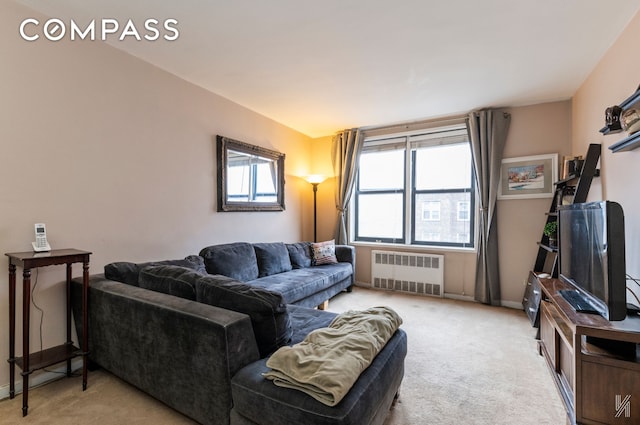 living area featuring radiator, a healthy amount of sunlight, light carpet, and baseboards