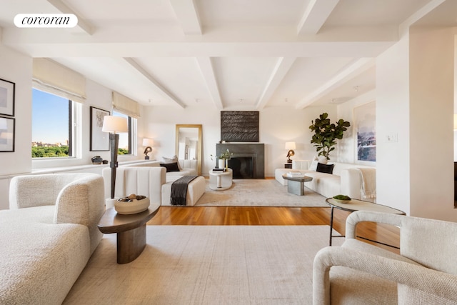 living room with a large fireplace, beam ceiling, and hardwood / wood-style floors