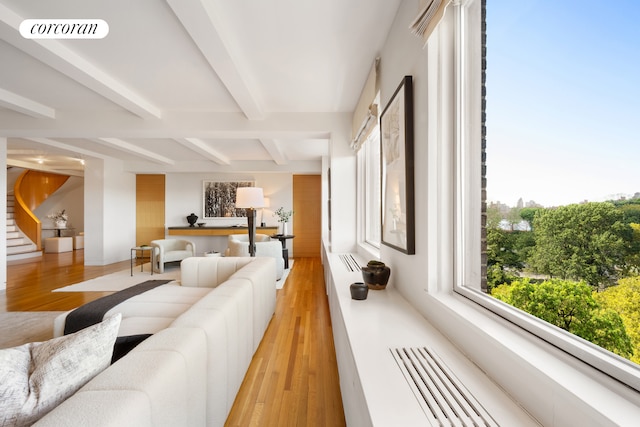 1158 5th Ave Unit 9/10A, New York City, NY 10029 - living room featuring beam ceiling, light wood finished floors, and stairway
