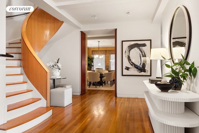 foyer entrance featuring a chandelier, stairway, and wood finished floors