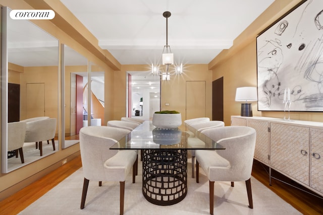 dining room with beam ceiling, wood-type flooring, and a chandelier