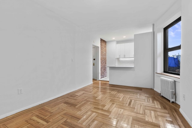 unfurnished living room with radiator and light parquet floors