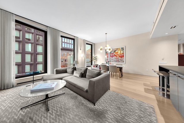 living area with light wood-type flooring, a notable chandelier, and baseboard heating