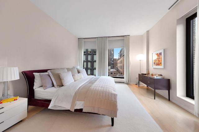 bedroom with expansive windows, baseboards, access to exterior, and light wood-style floors