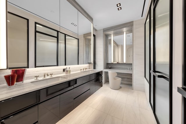 bathroom featuring double vanity, tile walls, a sink, and tile patterned flooring