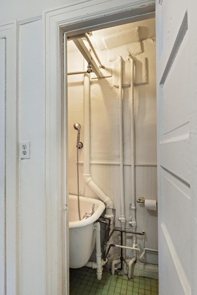 bathroom featuring tile patterned flooring, a freestanding tub, and a wainscoted wall