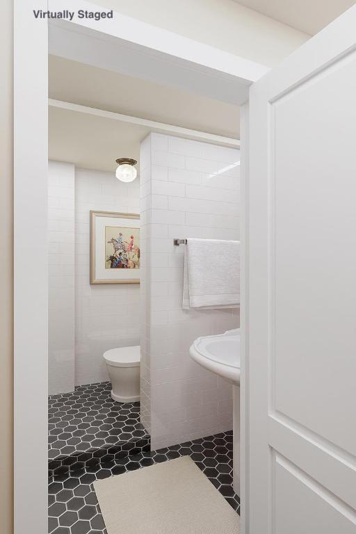 bathroom featuring toilet, tile walls, and a shower