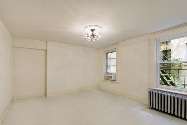 spare room with radiator heating unit, a chandelier, and cooling unit