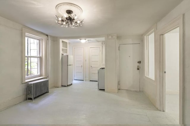 interior space featuring an inviting chandelier, radiator, and washer / dryer