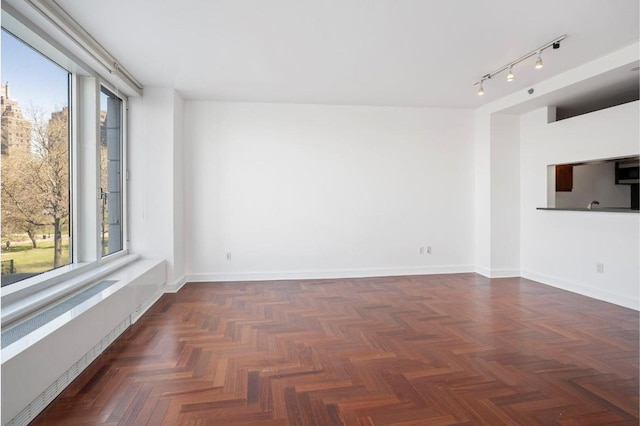 empty room featuring a healthy amount of sunlight and dark parquet floors