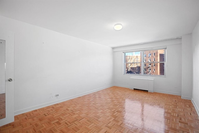 empty room with light parquet floors and radiator heating unit