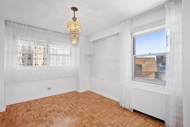 spare room featuring an inviting chandelier and light parquet floors