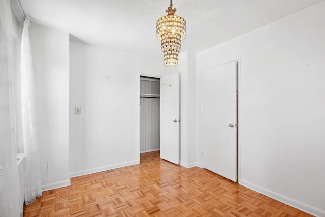 unfurnished bedroom with an inviting chandelier and light parquet flooring