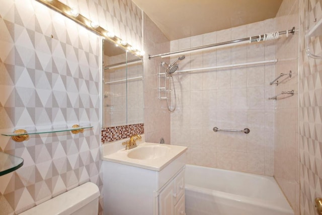 full bathroom featuring vanity, tiled shower / bath, and toilet