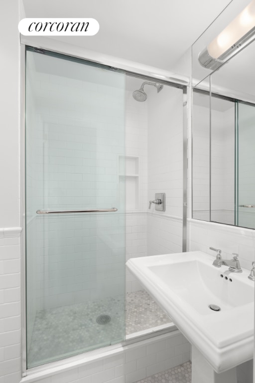 full bath featuring a stall shower, a sink, and tile walls