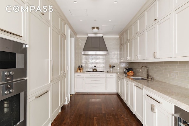 kitchen with island range hood, sink, white cabinets, stainless steel oven, and light stone countertops