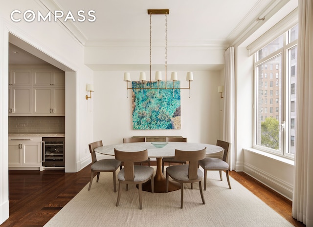 dining space with a chandelier, dark wood finished floors, beverage cooler, and crown molding