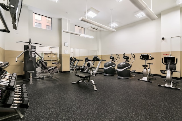 exercise room with a high ceiling and baseboards