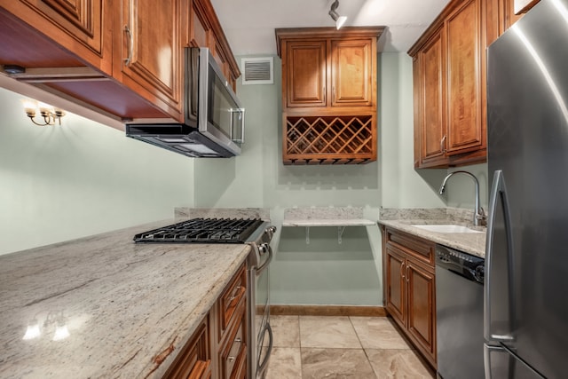 kitchen with stainless steel appliances, light stone counters, and sink