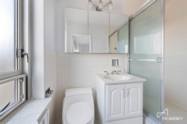 bathroom featuring toilet, radiator, vanity, a shower stall, and tile walls