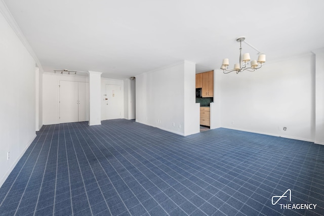 spare room with baseboards, rail lighting, dark colored carpet, crown molding, and a chandelier