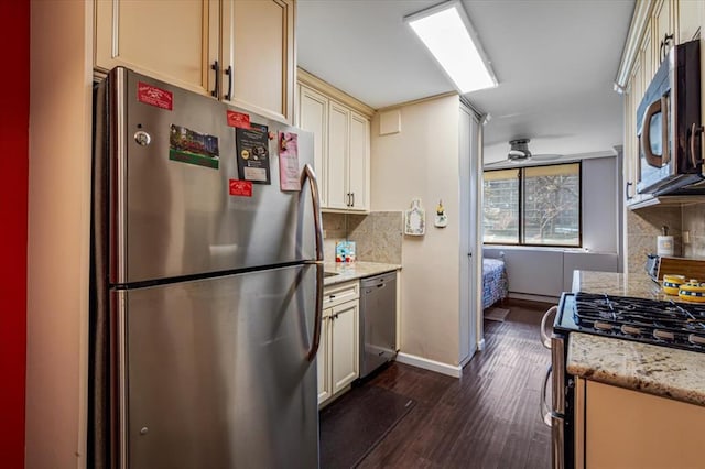 kitchen with light stone counters, appliances with stainless steel finishes, cream cabinets, and decorative backsplash