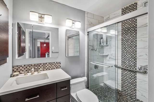 bathroom with tasteful backsplash, vanity, toilet, and a shower with shower door