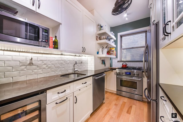kitchen with appliances with stainless steel finishes, a sink, white cabinetry, tasteful backsplash, and wine cooler