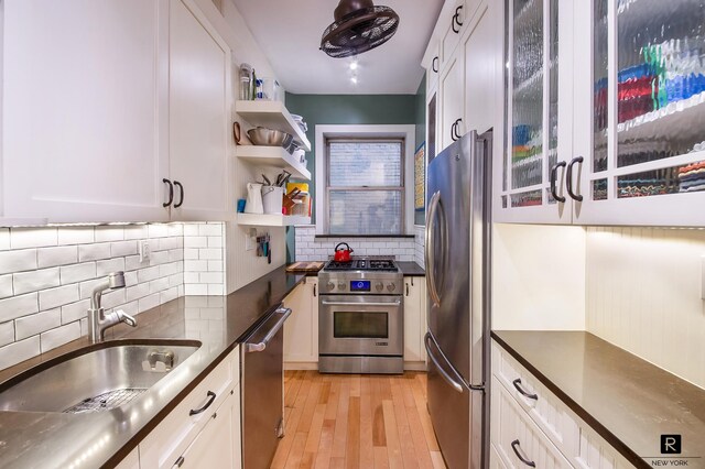 kitchen featuring dark countertops, appliances with stainless steel finishes, white cabinetry, and a sink