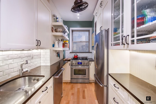 kitchen with white cabinets, stainless steel appliances, dark countertops, and a sink