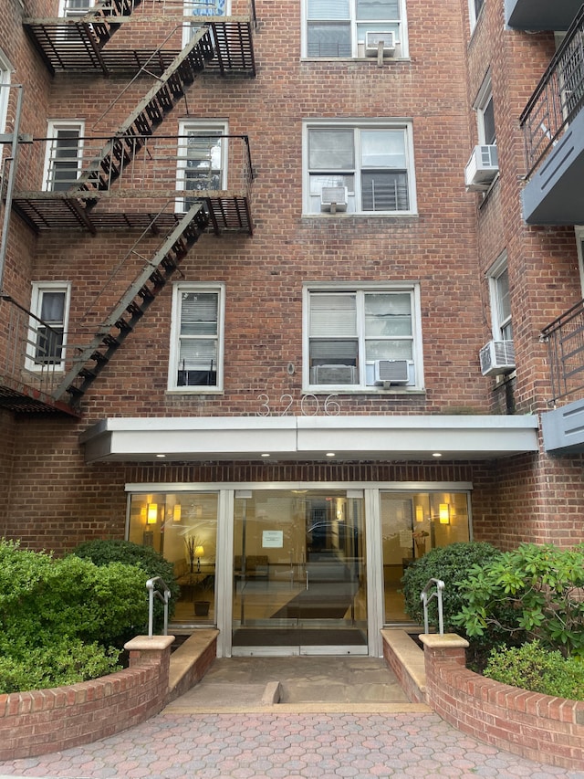 view of exterior entry featuring cooling unit and brick siding