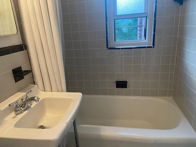 bathroom with shower / bathtub combination with curtain and sink