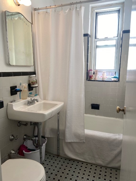 bathroom featuring shower / tub combo with curtain, toilet, tile patterned flooring, and tile walls