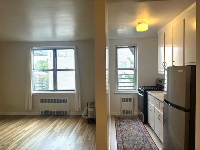 kitchen with white cabinetry, stainless steel appliances, and radiator heating unit