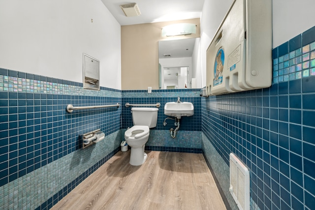 bathroom featuring hardwood / wood-style flooring, toilet, sink, and tile walls