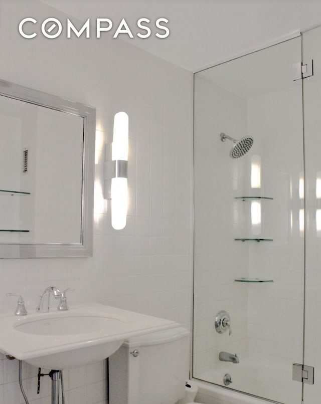 bathroom with tile walls, toilet, backsplash, and enclosed tub / shower combo