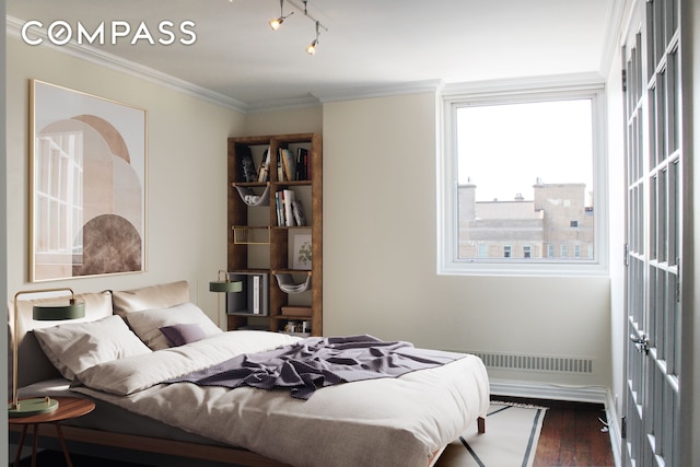 bedroom with dark wood finished floors, rail lighting, and ornamental molding