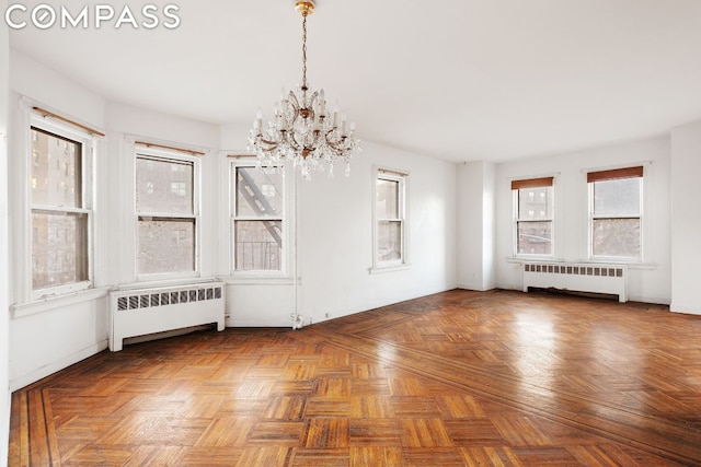 unfurnished dining area with parquet floors, radiator heating unit, and a chandelier