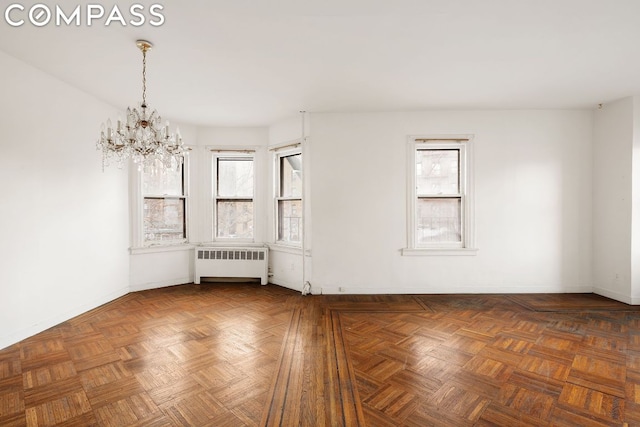 empty room featuring radiator, a notable chandelier, and dark parquet floors