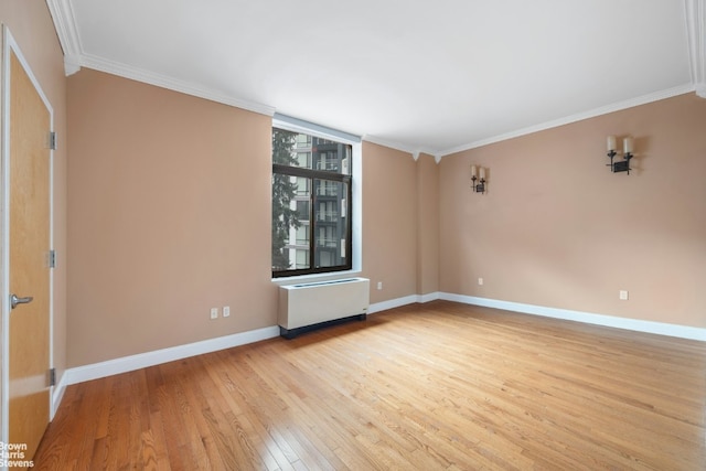 spare room featuring crown molding, radiator heating unit, and light hardwood / wood-style floors