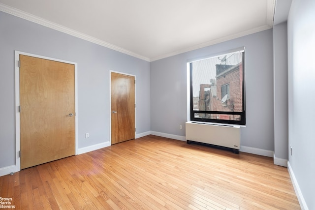 unfurnished bedroom featuring radiator heating unit, crown molding, and light hardwood / wood-style flooring