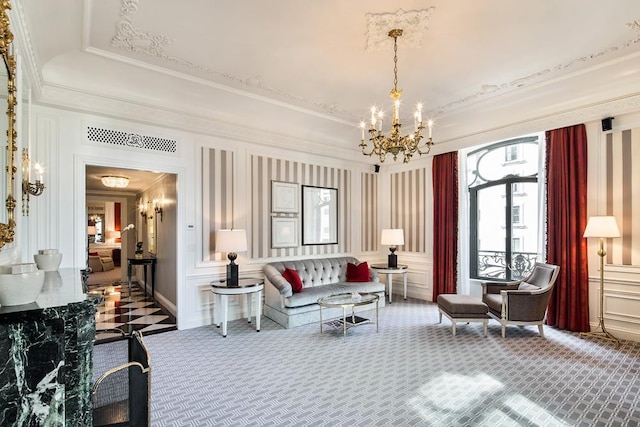 carpeted living room with a tray ceiling, a chandelier, crown molding, and a decorative wall