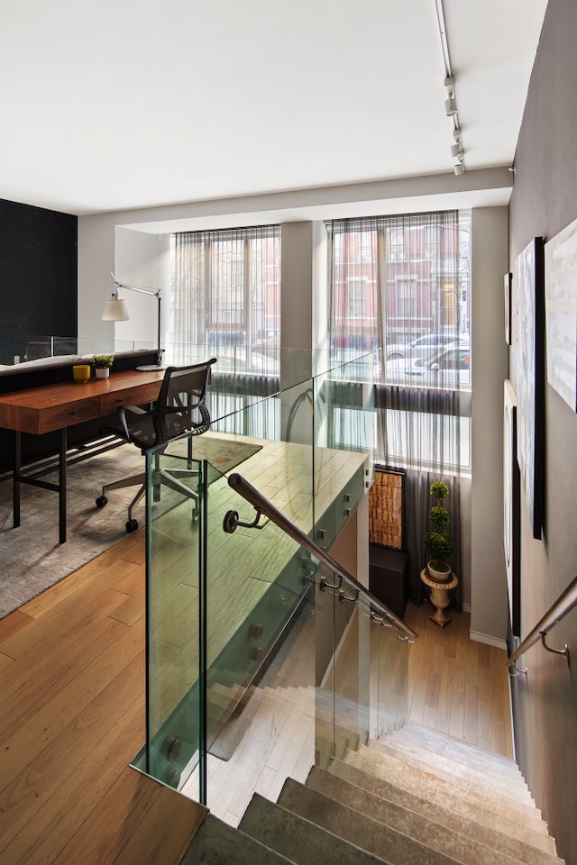 stairs featuring rail lighting and hardwood / wood-style flooring