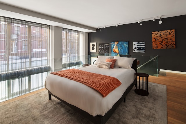 bedroom featuring wood finished floors and track lighting