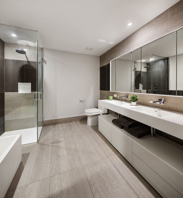 bathroom featuring a washtub, decorative backsplash, toilet, a stall shower, and a sink