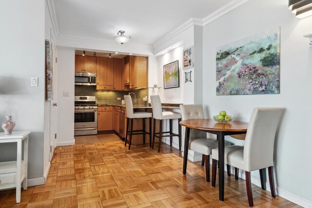 kitchen featuring backsplash, ornamental molding, light parquet flooring, and appliances with stainless steel finishes