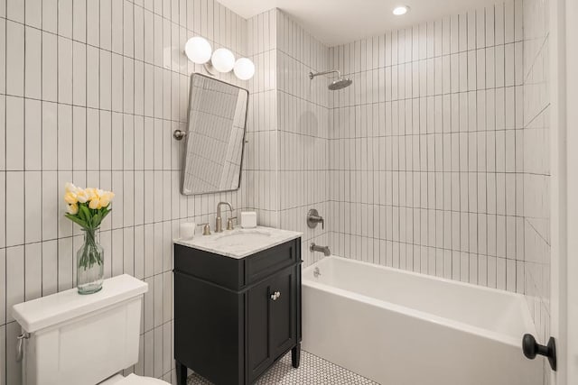 full bathroom featuring tiled shower / bath combo, vanity, tile walls, and toilet