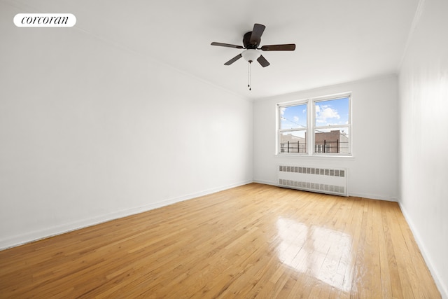 unfurnished room featuring ceiling fan, ornamental molding, radiator, and light hardwood / wood-style floors