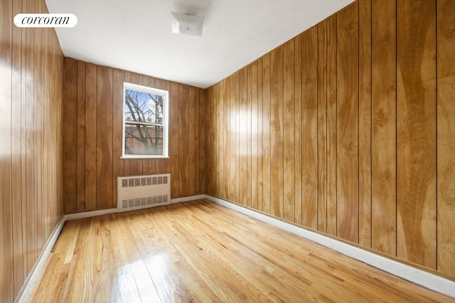 unfurnished room with radiator, hardwood / wood-style floors, and wood walls