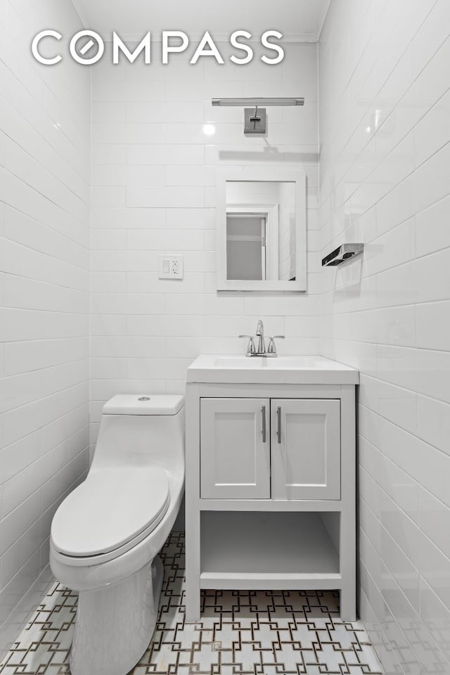 half bath featuring toilet, tile walls, and vanity